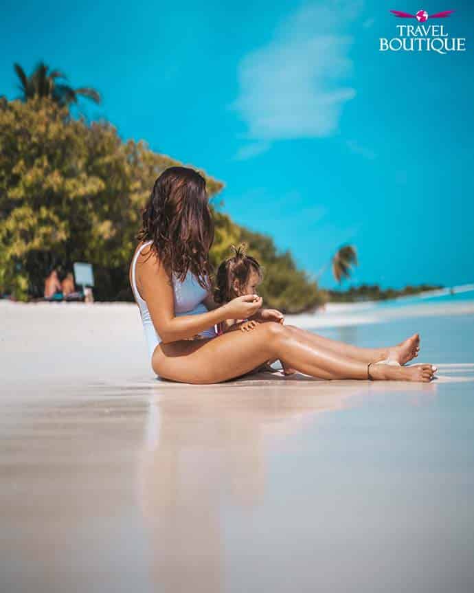 žena i beba sede na plaži na Maldivima